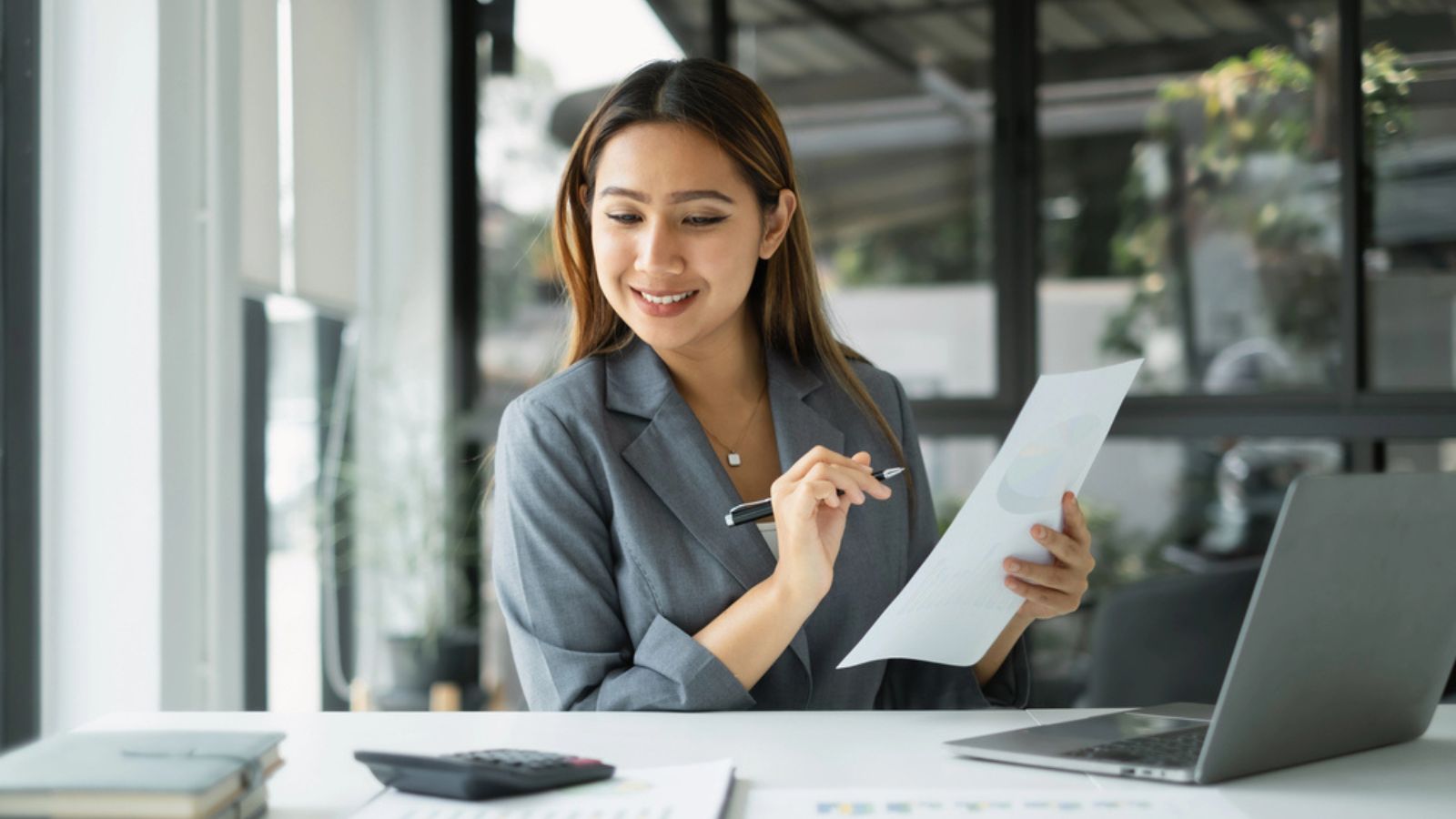Asian businesswoman sit at their desks and calculate financial graphs showing results about her investments