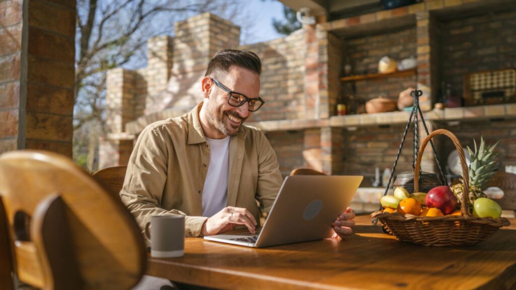 Man Caucasian Work on Laptop Computer on Terrace Happy Smile Success. Work Concept.