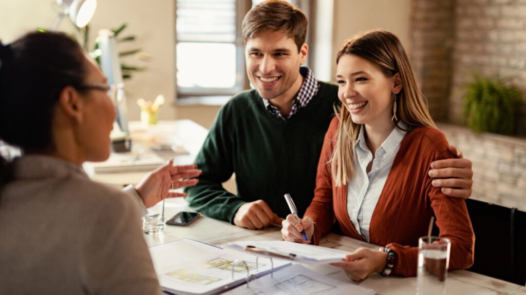 Young happy couple signing a contract while being on a meeting with insurance agent in the office. Meeting with financial advisor. Money Concept