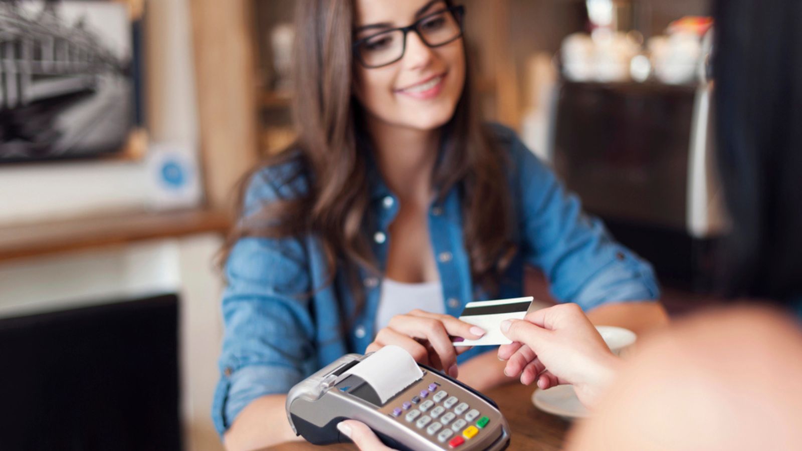 Smiling woman paying for coffee using credit card