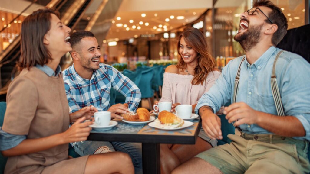Group of friends having a coffee together.Young men and women sitting at cafe table and smiling.