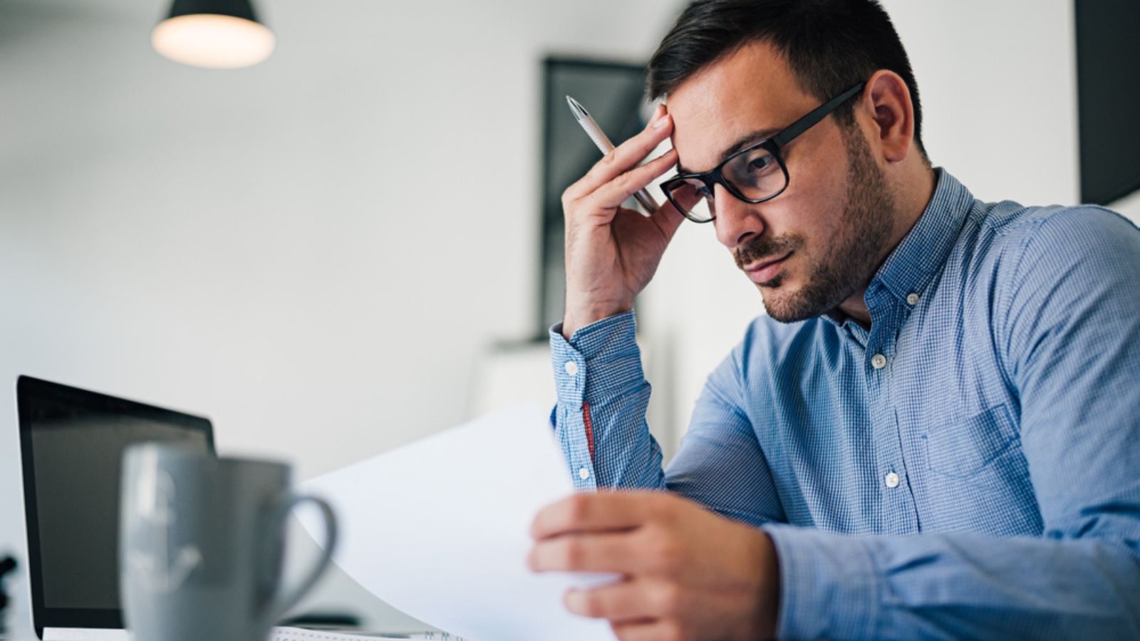 stressed out and worried troublesome overworked businessman entrepreneur looking documents report in modern bright office working under pressure and tight deadline