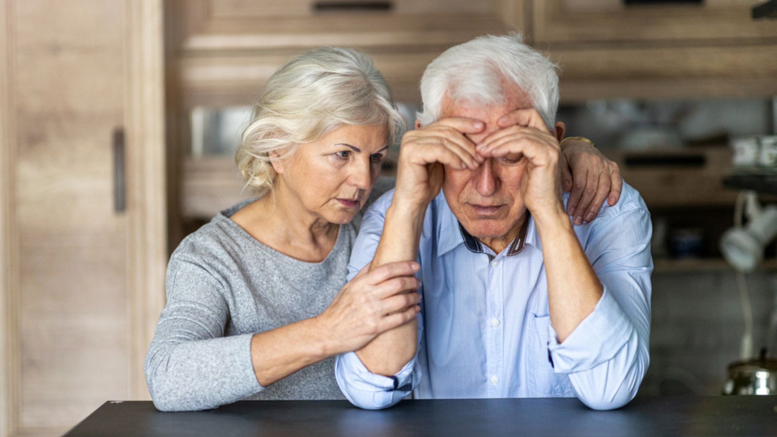 Senior woman comforting her husband at home. Old couple, senior couple