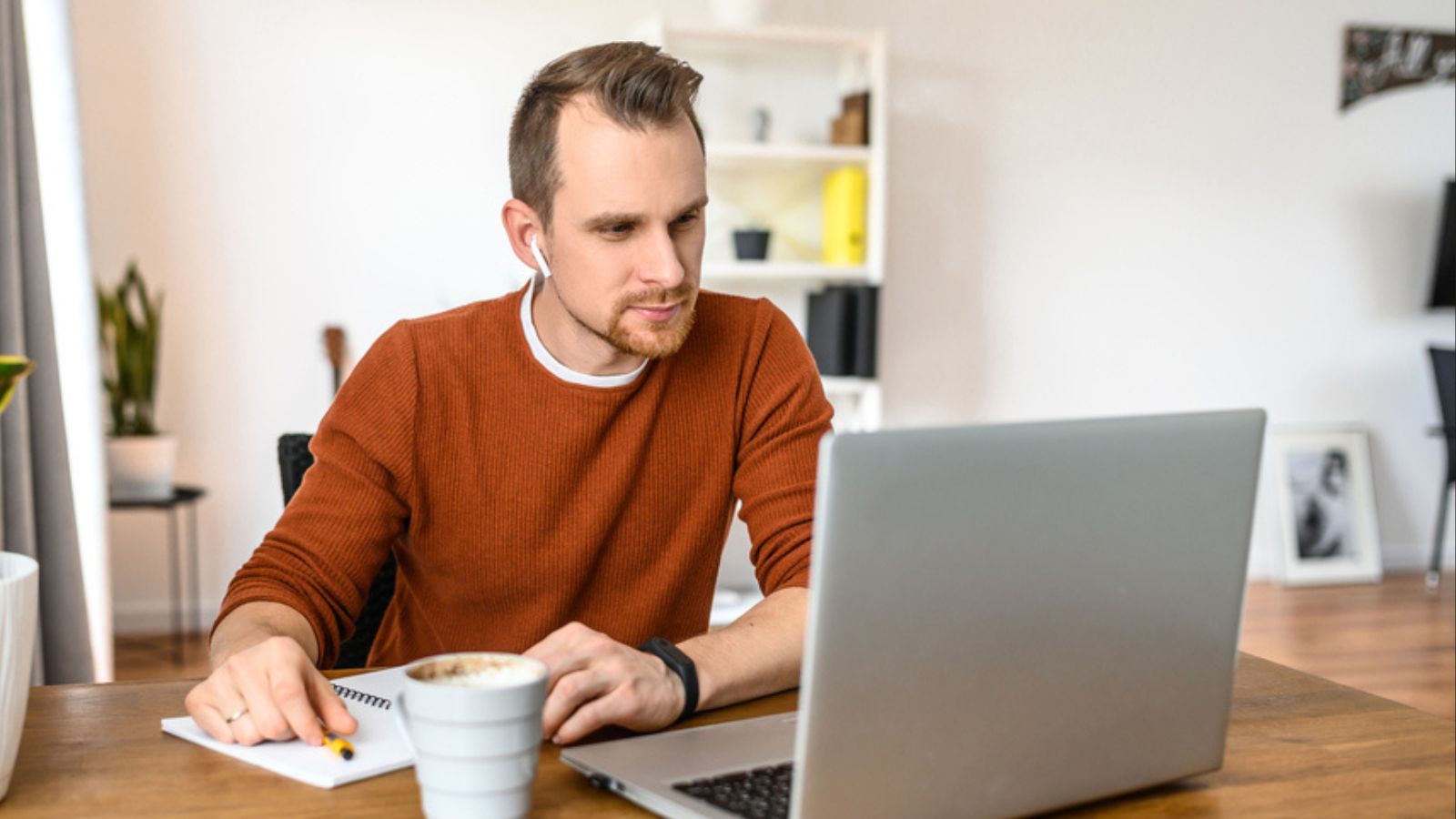 Guy looks at laptop and notes in notebook