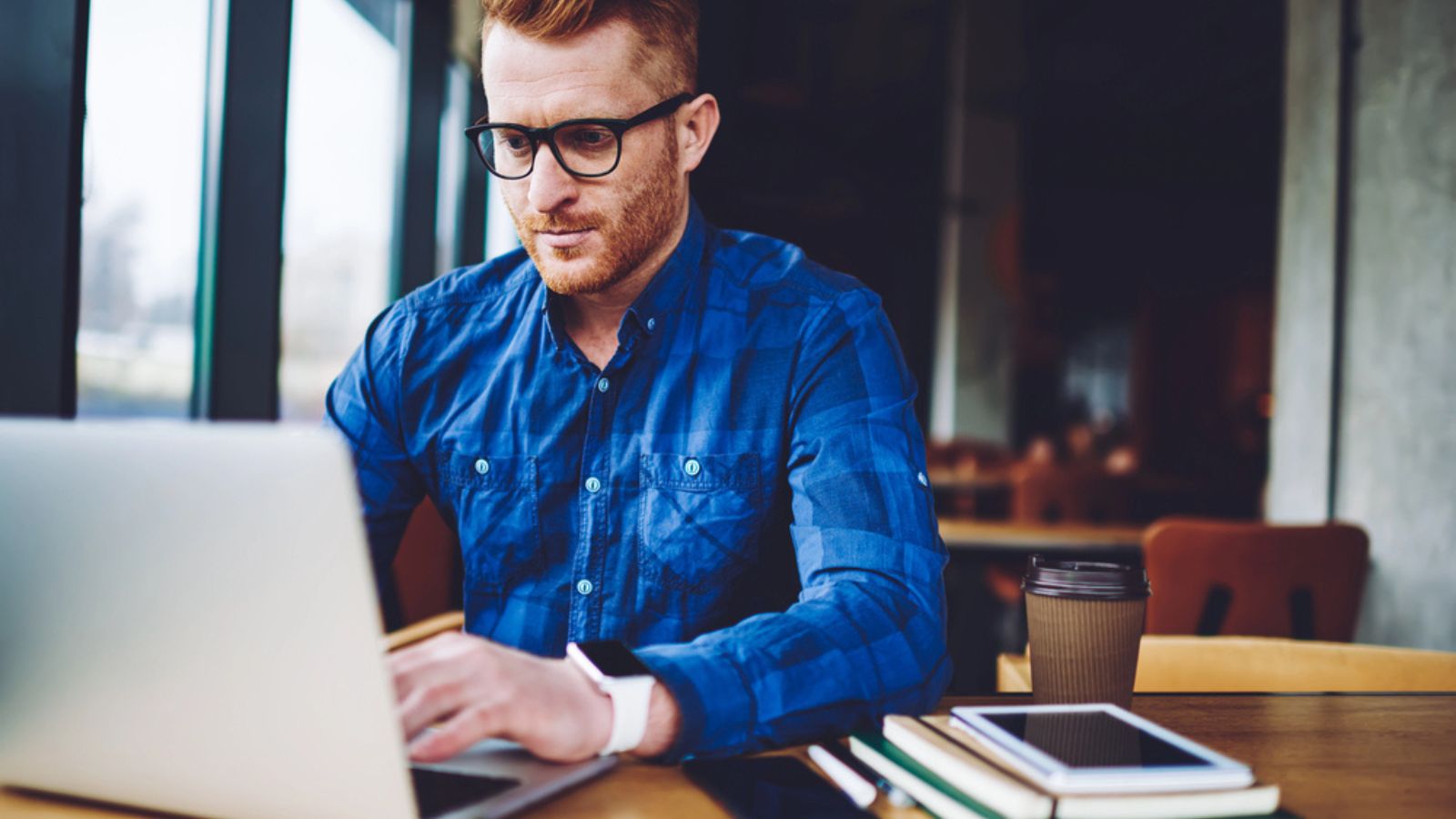 Concentrated male freelancer searching information for creating and programming new website for company order, reading news about internet provider via laptop