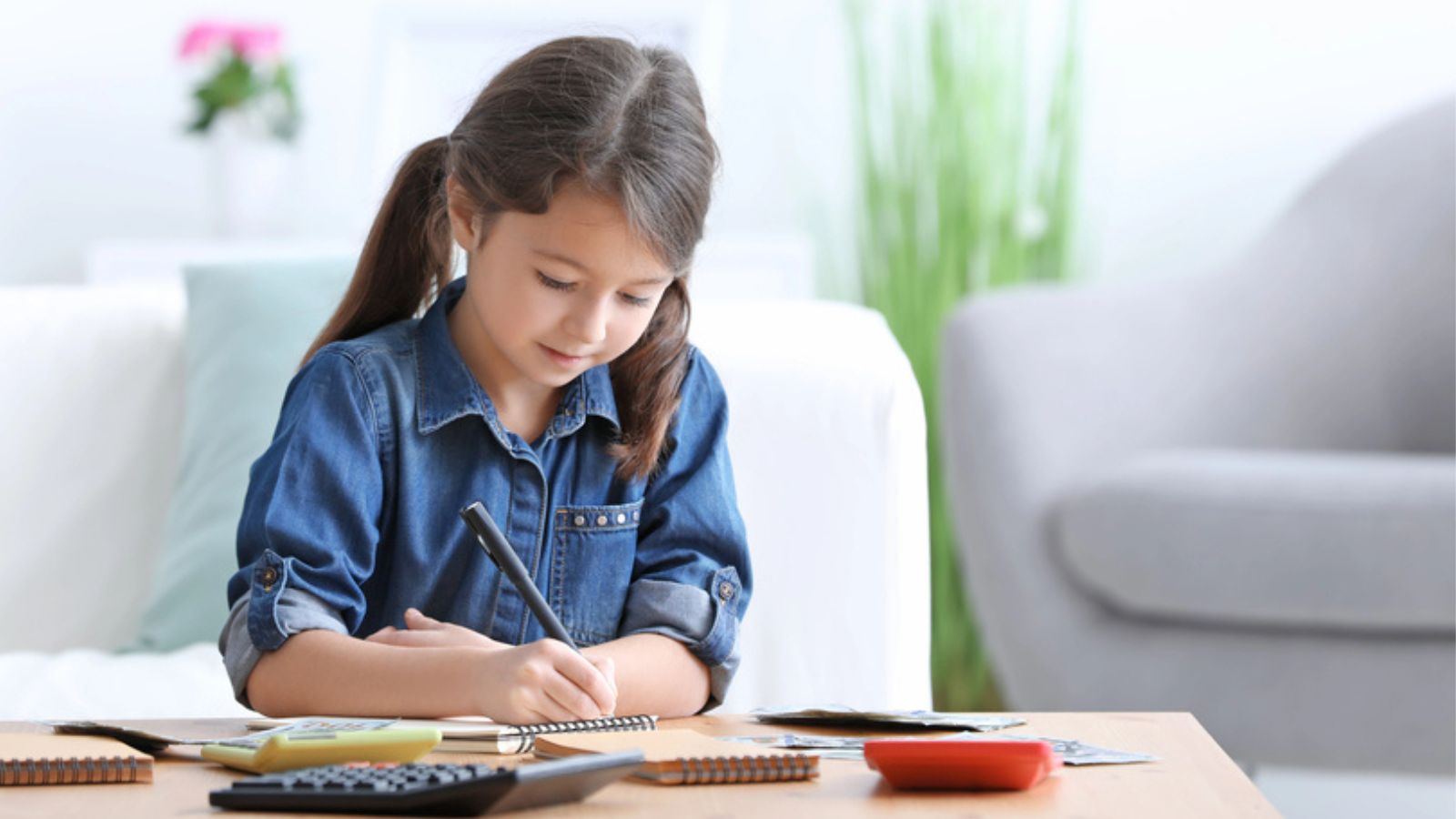 Little girl counting money at table indoors