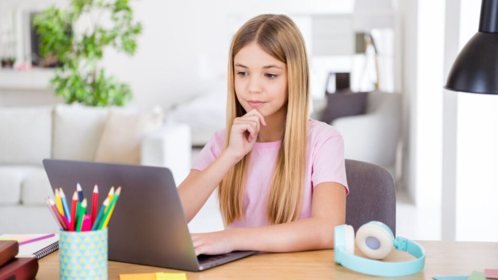 Photo of smart a-level kid girl sit table desk study remote use laptop have lesson task brainstorming solution answer touch hand chin in house indoors