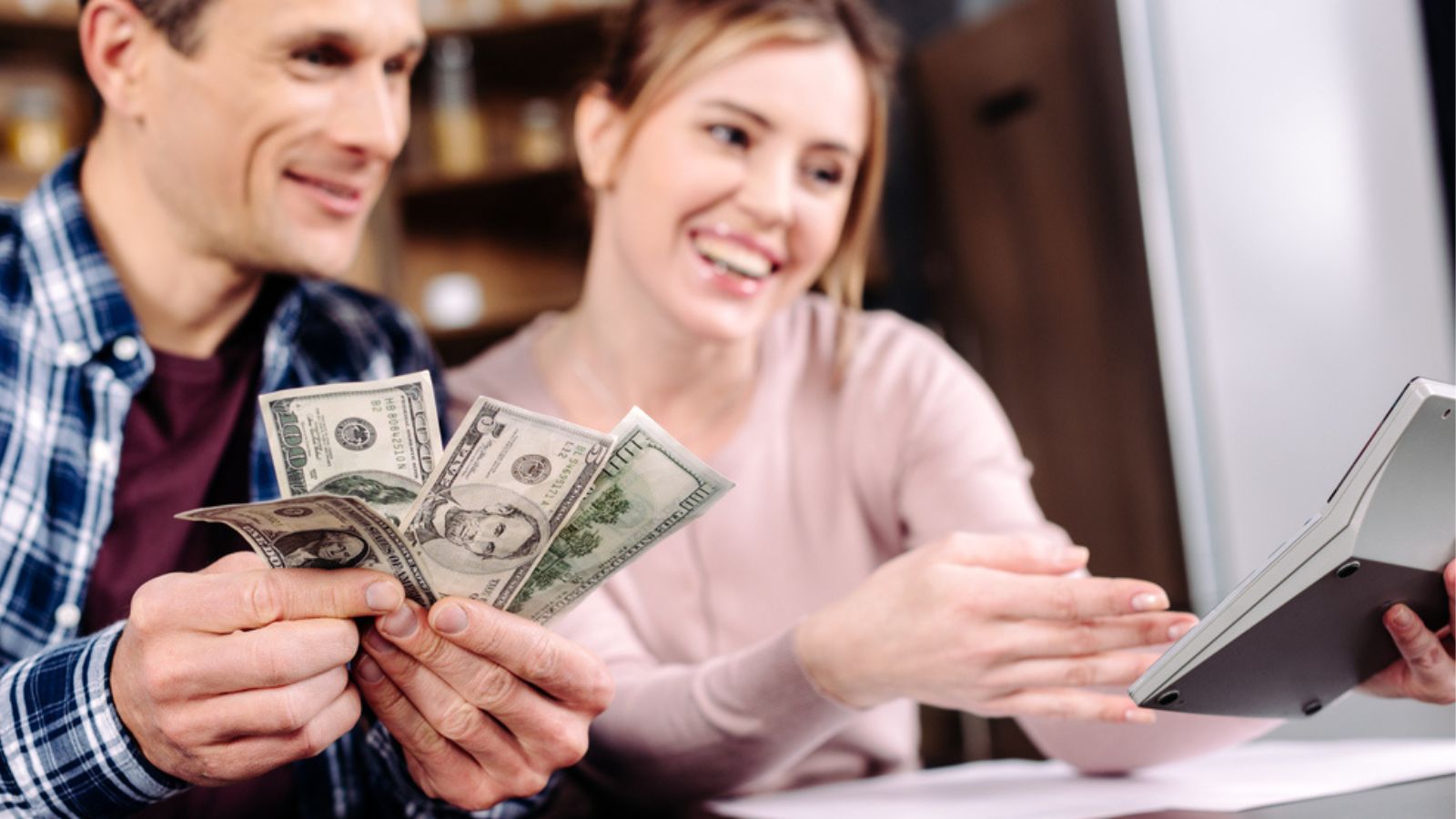 Portrait of happy couple counting money together at home