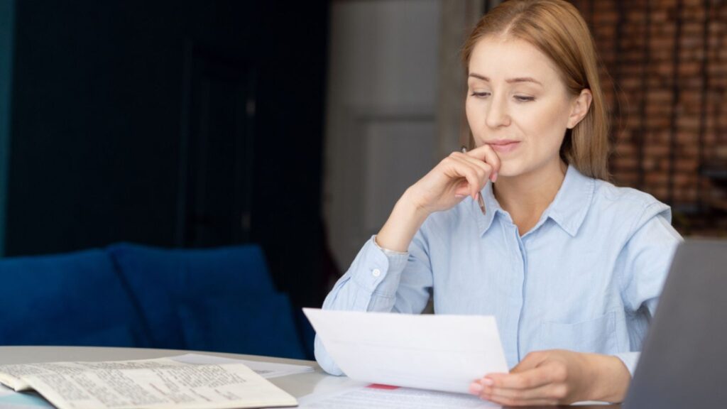 Portrait of thinking businesswoman carefully reading documents with her laptop