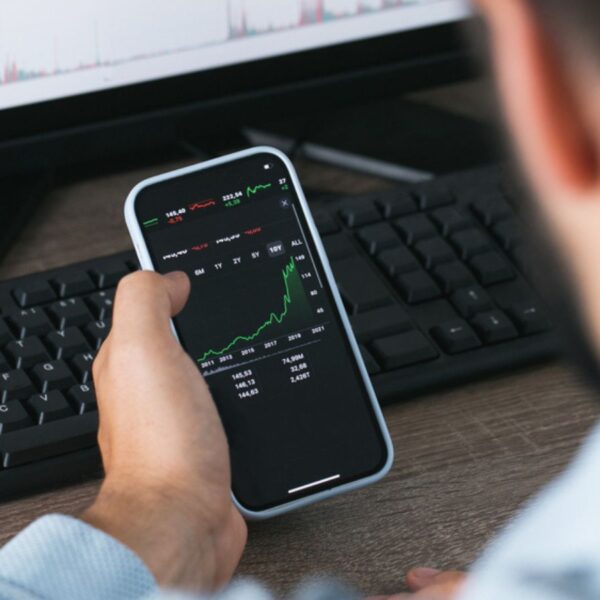 Stock market phone in the hand and desktop computer green and red charts