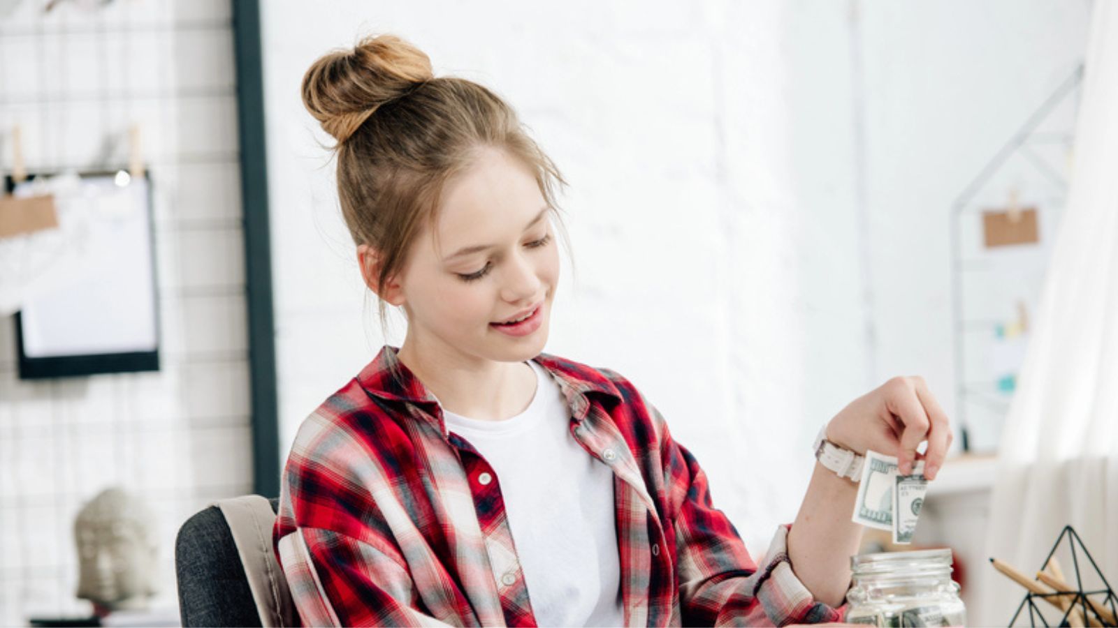 Teenager in checkered shirt putting money in a glass