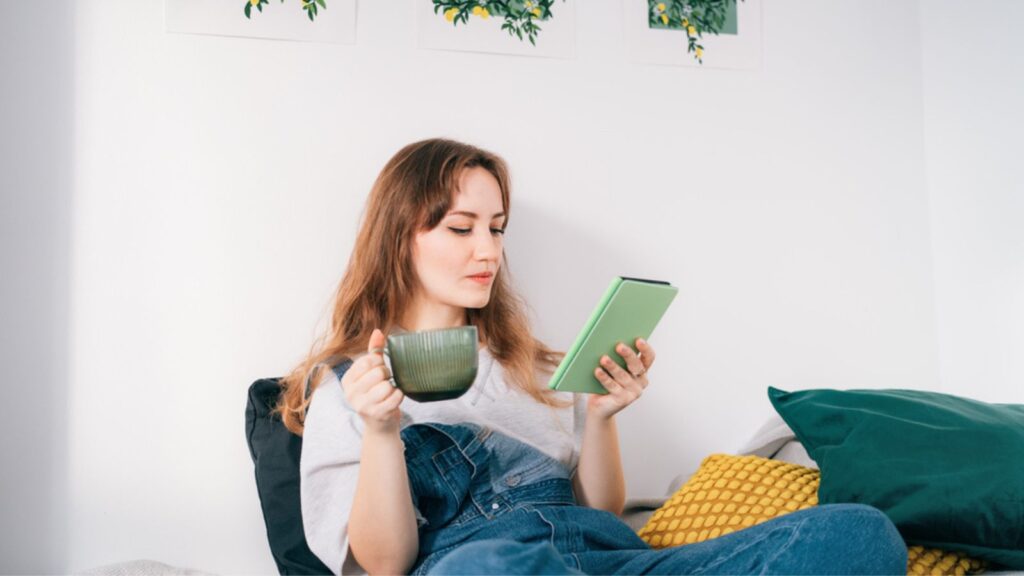 Young woman reading e-book on tablet reader in bed