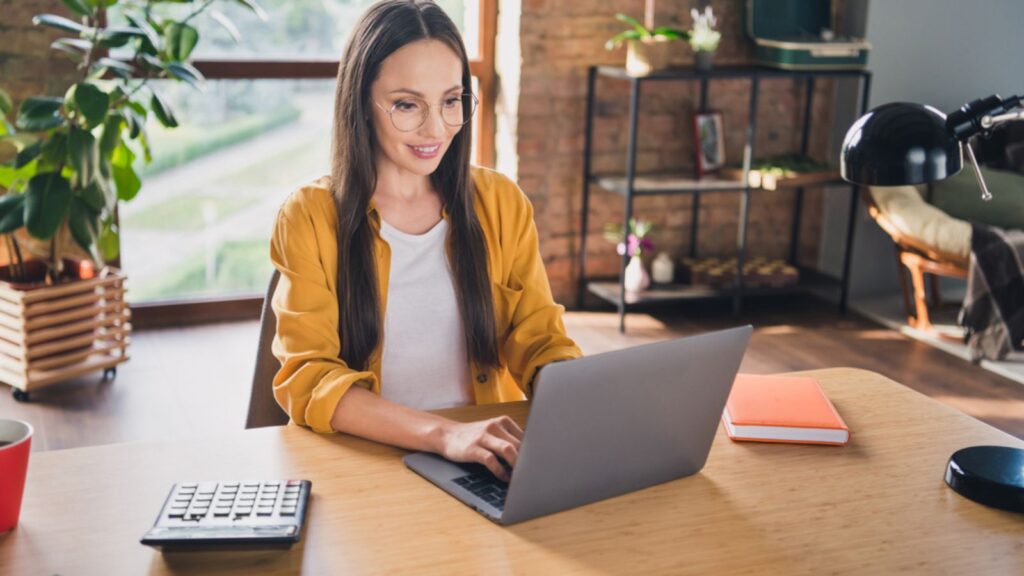 Pretty sweet mature woman wear yellow shirt glasses smiling using laptop at home