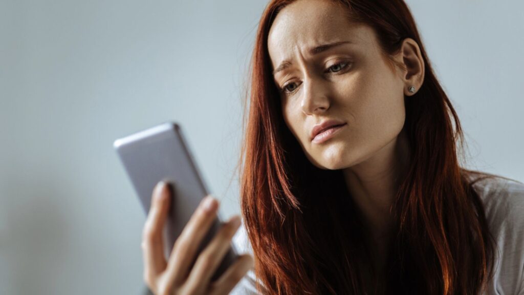 Sad Cheerless young woman looking at her phone. People Concept. Psychology