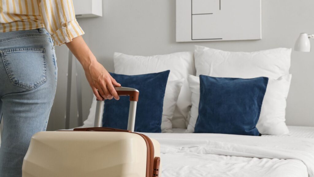 Woman with suitcase in light hotel room, closeup